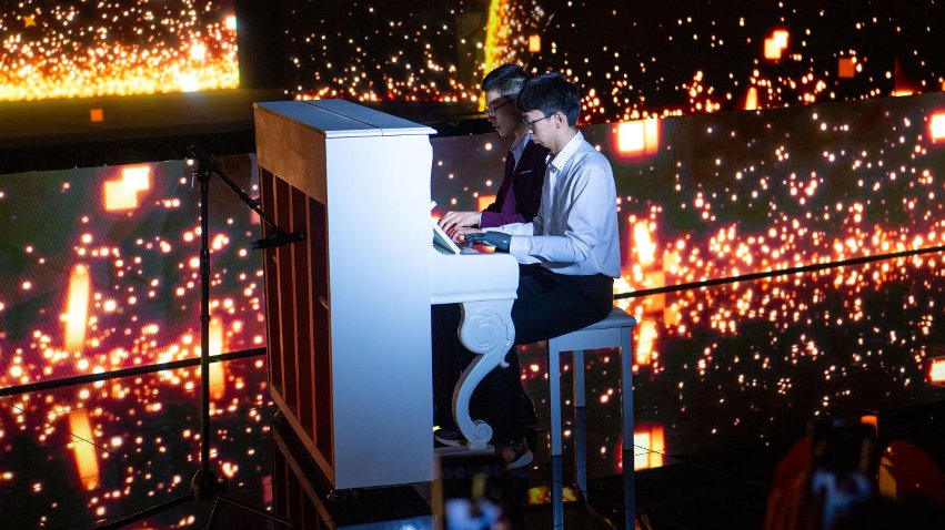 智能仿生手使用者古月與少年鋼琴家舒海峰合奏。主辦方供圖